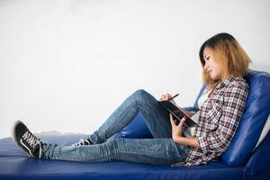 Young hipster woman  writing on notepad lying at home . photo