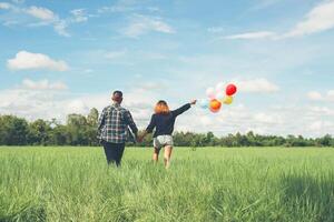 Back of happy young asian couple holding balloon and walk together. photo