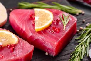 Fresh tuna fillet steaks with spices and herbs on a black background