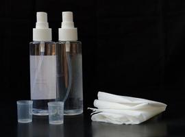 Hand sanitizer with tissue isolated on black background photo