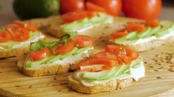 Tomatos and avocado on black table close up video