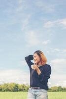 Hipster woman standing on grassland holding coffee and enjoying fresh air photo