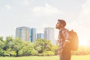 Young hipster man enjoys the town view from park while traveling photo