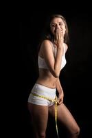 Beautiful young woman measuring her figure size with tape measure photo