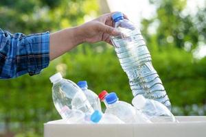 voluntario de mujer asiática llevar botellas de plástico de agua a la basura foto