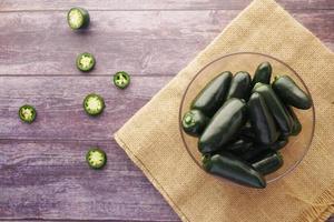 fresh Jalapeno peppers in a bowl on table, top view photo