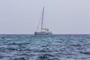 catamarán de velero blanco en el océano cerca de la playa. foto