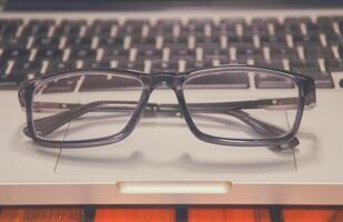 Gafas en el teclado de la computadora portátil de oficina foto