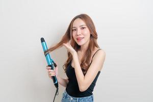 Portrait beautiful Asian woman using hair curler or curling iron on white background photo