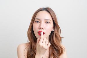 Retrato hermosa mujer asiática haciendo y usando lápiz labial rojo sobre fondo blanco. foto