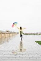 Beautiful brunette woman holding colorful umbrella walking in the rain photo