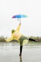Beautiful brunette woman holding colorful umbrella out in the rain photo