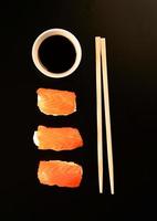 Set of sushi rolls and chopsticks, isolated on black background photo