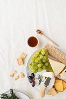 Cheese plate assortment served with honey, grapes, bread and rosemary photo