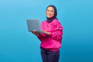 Joven mujer sonriente feliz sosteniendo un portátil y enviando un correo electrónico foto