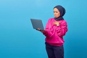 Portrait of shocked surprised girl standing and holding laptop photo