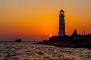 Lighthouse on the sea coast at sunset photo