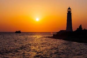 Lighthouse on the sea coast at sunset photo