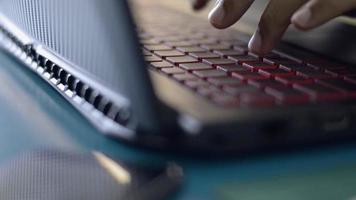 manos del empresario escribiendo el teclado del ordenador portátil en la mesa de trabajo en casa. video