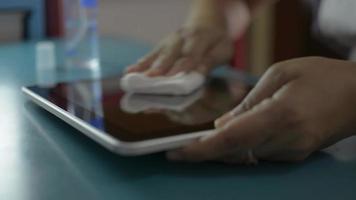 Woman cleaning and disinfection on surfaces of digital tablet. video