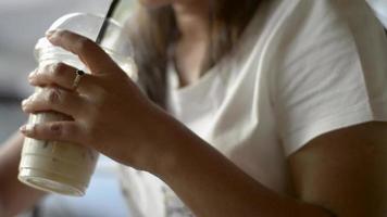 woman texting message on mobile phone drinking ice coffee. video