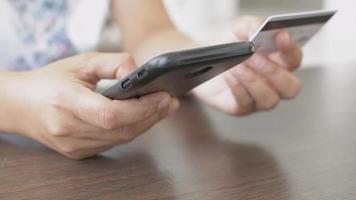 mulher fazendo compras online no smartphone com cartão de crédito em casa. video