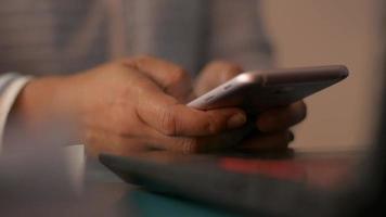 Woman hands texting message on mobile smart phone at working desk. video