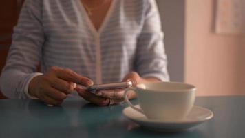 affärskvinna som använder smart telefon på skrivbordet och dricker kaffe. video