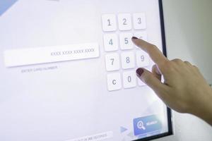female hand dials a pin code at an ATM photo