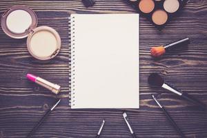 Top view a collection of cosmetic makeup and notebook on wooden table. photo