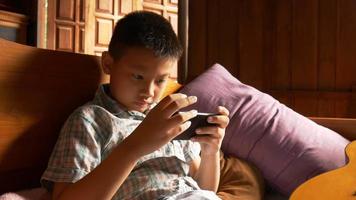 Boy playing games with mobile phone online at home video