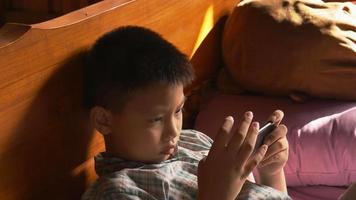 garçon jouant à des jeux avec un téléphone portable en ligne à la maison video