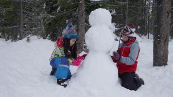 Two children building snowman together video