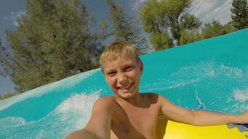 giovane ragazzo che scende da uno scivolo acquatico al parco acquatico, video pov
