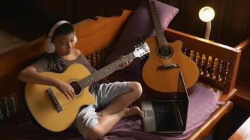 niño aprende a tocar la guitarra en línea en casa video