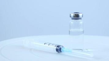 les mains dans des gants médicaux bleus tiennent une seringue et un flacon en verre avec le vaccin.