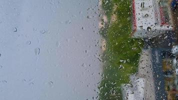 gotas de lluvia en primer plano de la ventana. clima otoñal nublado. video vertical.