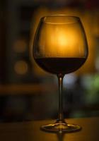 Copa de vino tinto merlot francés en el oscuro y acogedor bar interior foto