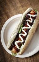 Classic hot dog with frankfurter sausage and sauces on wood table photo