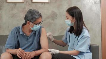 una doctora asiática está vacunando a un anciano en su casa. video
