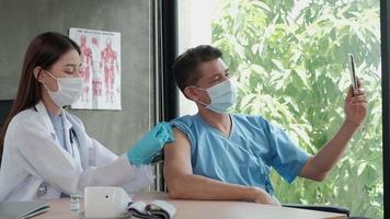Patient macht ein Selfie-Porträt, während ein Arzt impft. video