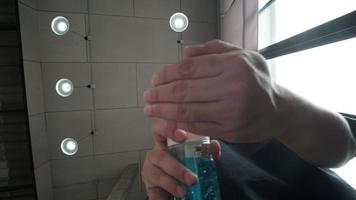 A man is cleaning his hands and fingers with an alcohol gel.