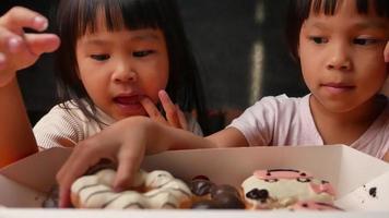 glad bedårande liten flicka plockar upp söta munkar ur lådan. video