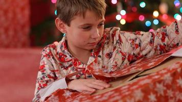 Junge reißt Papier vom Weihnachtsgeschenk ab video
