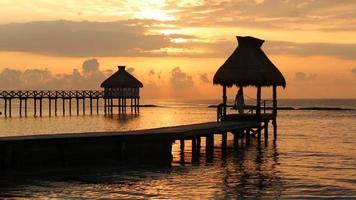 la donna cammina lungo il molo durante il tramonto al resort tropicale video