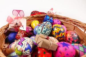 Coloridos huevos de pascua y caja de regalo en una canasta de madera foto