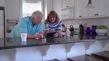 casal sênior usando tablet digital juntos video