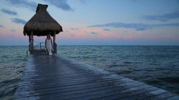 Woman walks down pier at tropical resort video