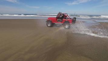 prise de vue aérienne d'un véhicule tout terrain 4x4 roulant sur la plage video