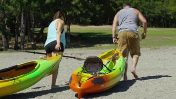 Couple carry kayaks to lake video